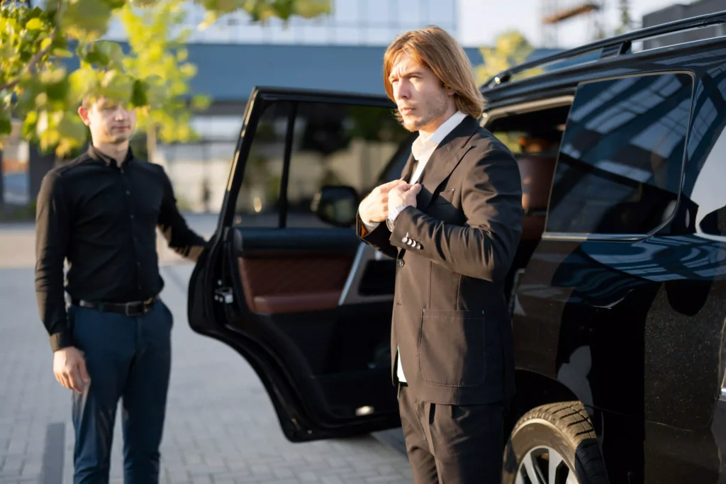 Luxury Black Car Service Annapolis providing premium transportation. A chauffeur assists a businessman stepping out of a black SUV in a professional setting.