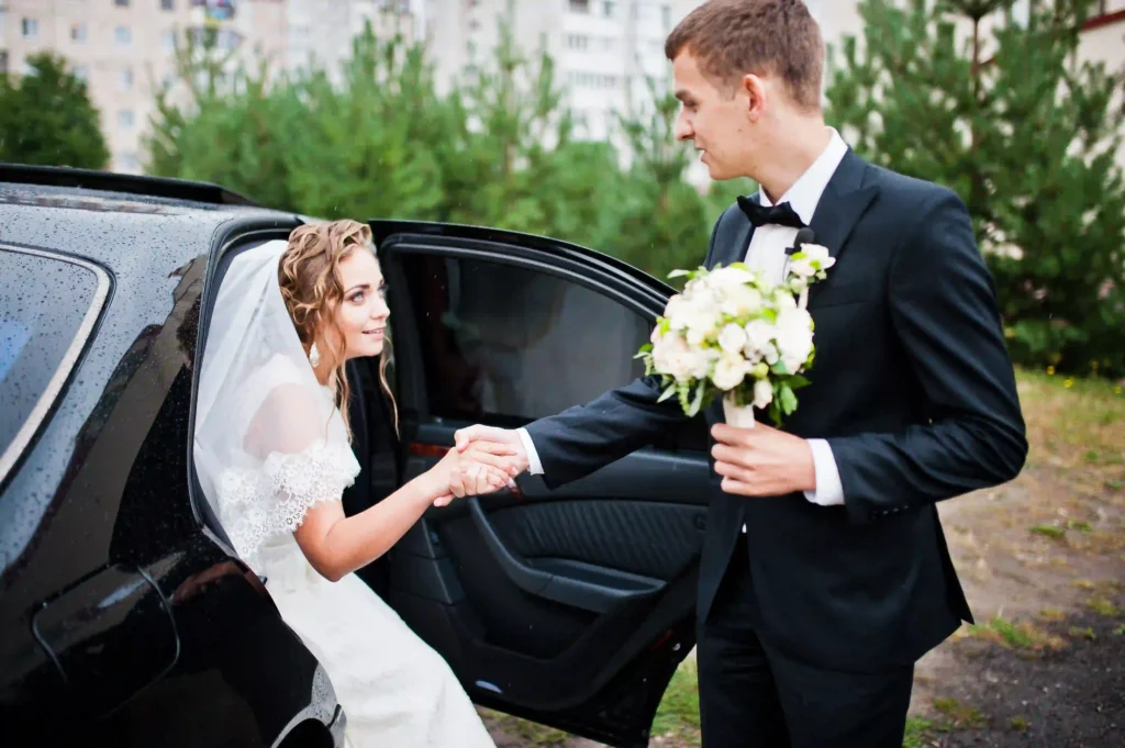 A groom helps his bride out of a luxury black car on their wedding day. Black Car Service Annapolis offers elegant transportation for special occasions.