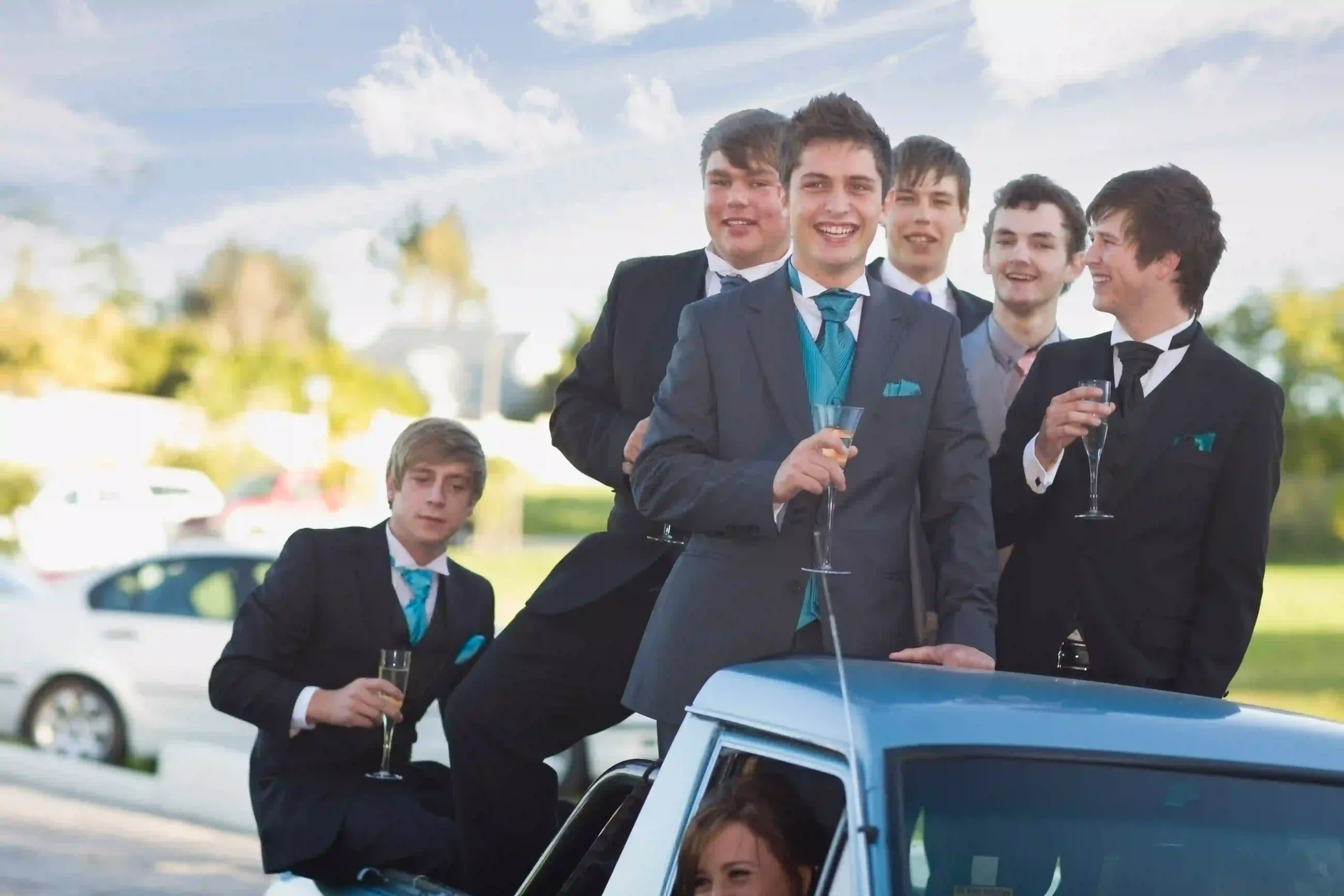 A group of Teens in suits celebrate with champagne in a luxury car. Arrive in style with Black Car Service Annapolis, offering premium event transportation.