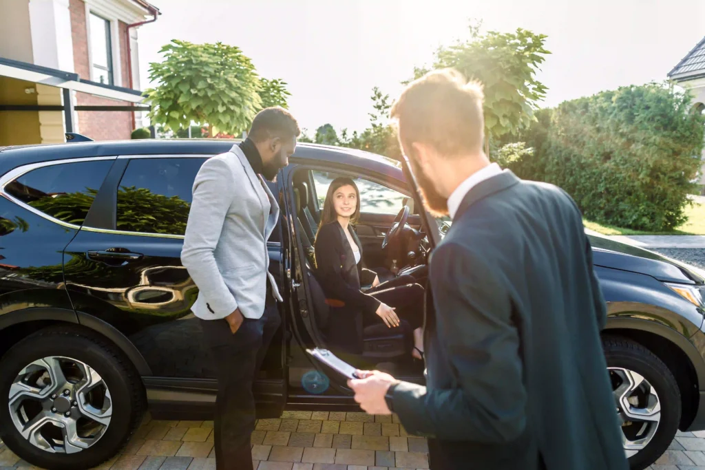 Professional Black Car Service Annapolis offering luxury transportation. A businesswoman steps out of a black SUV as two men assist her in a formal setting.